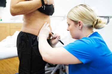 Medical professional administering treatment to a patient in a clinical setting.