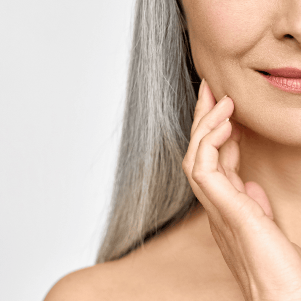 Close-up of a woman touching her jawline, highlighting facial contours.