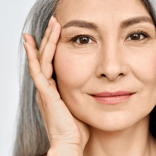 Close-up of a mature woman with clear skin touching her face.