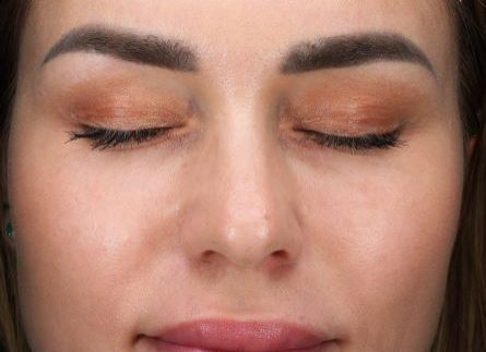 Close-up of a woman's face with closed eyes and smooth skin.