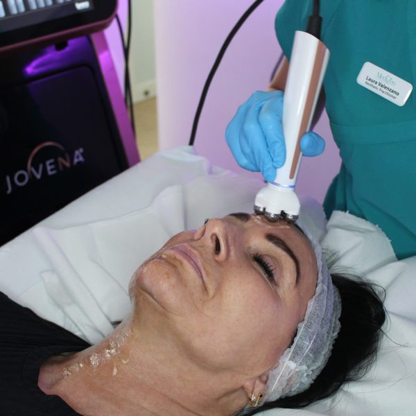 Woman receiving a facial treatment with a modern device at MediZen clinic.